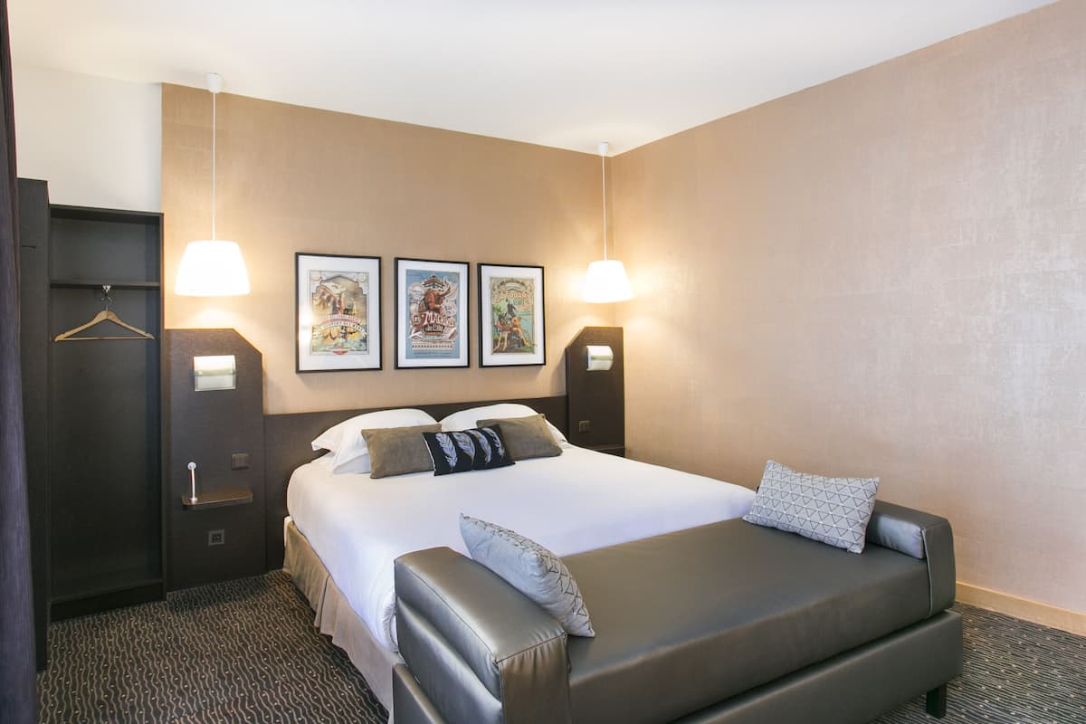 Een hotelkamer met een bed, een slaapbank, een kledingkast en kunstwerken aan de muur.
