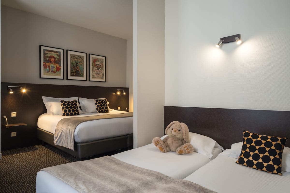 Een hotelkamer met twee bedden, een hoofdeinde, een wandlamp en een lijst met een afbeelding boven de bedden.