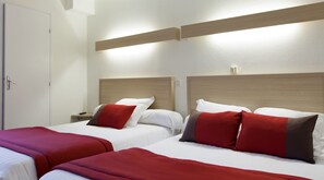 A hotel room with two beds, each with red and white bedding, and a wooden headboard. - Hôtel Chateaubriand (Nantes)