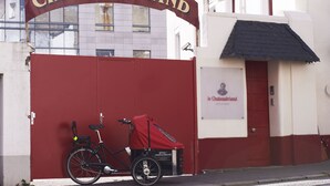 Una bicicleta estacionada frente a la entrada de un hotel con un portón rojo y un letrero que dice 'Hotel Chateaubriand'.