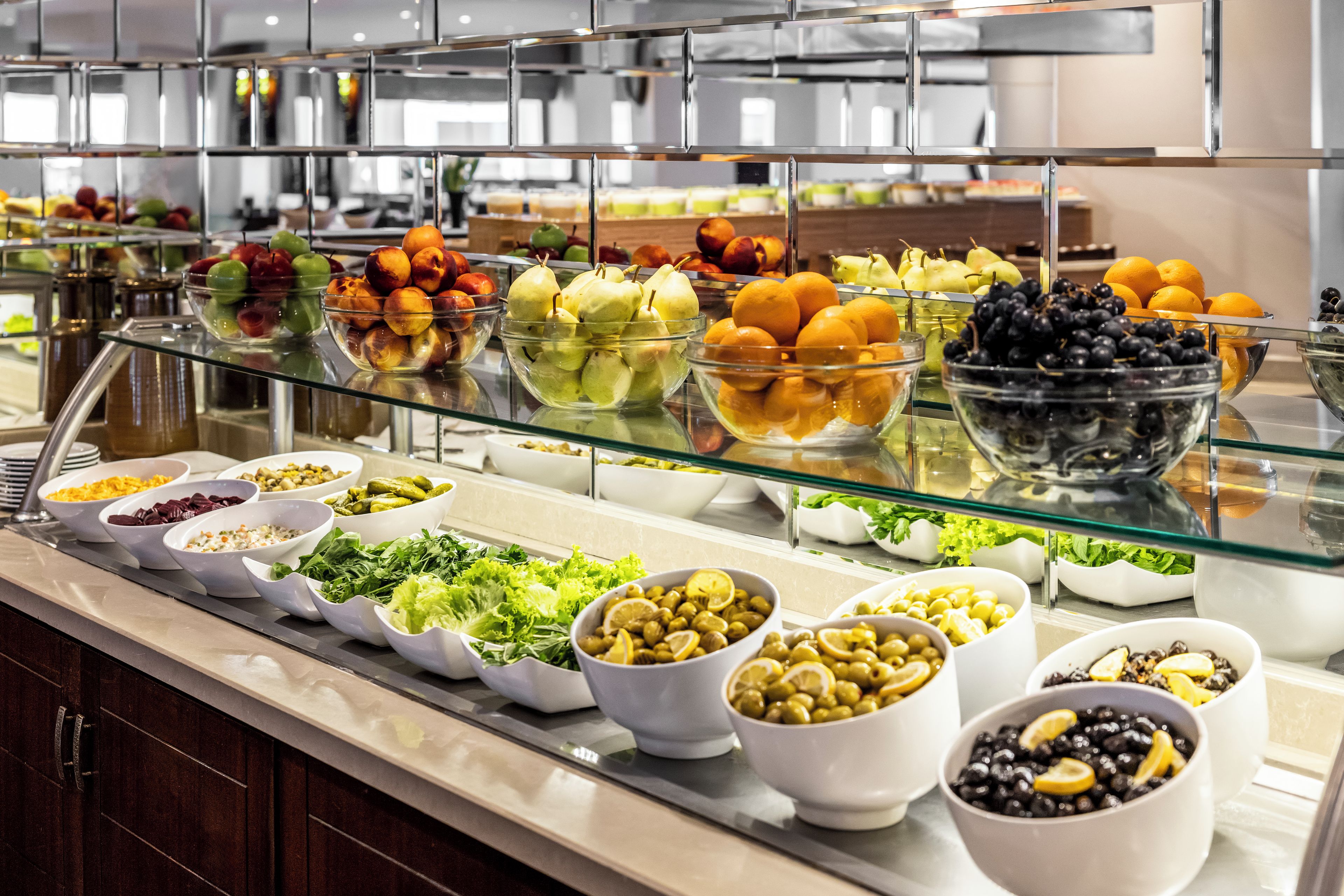 A buffet with various food items including fruits, vegetables, and salads.