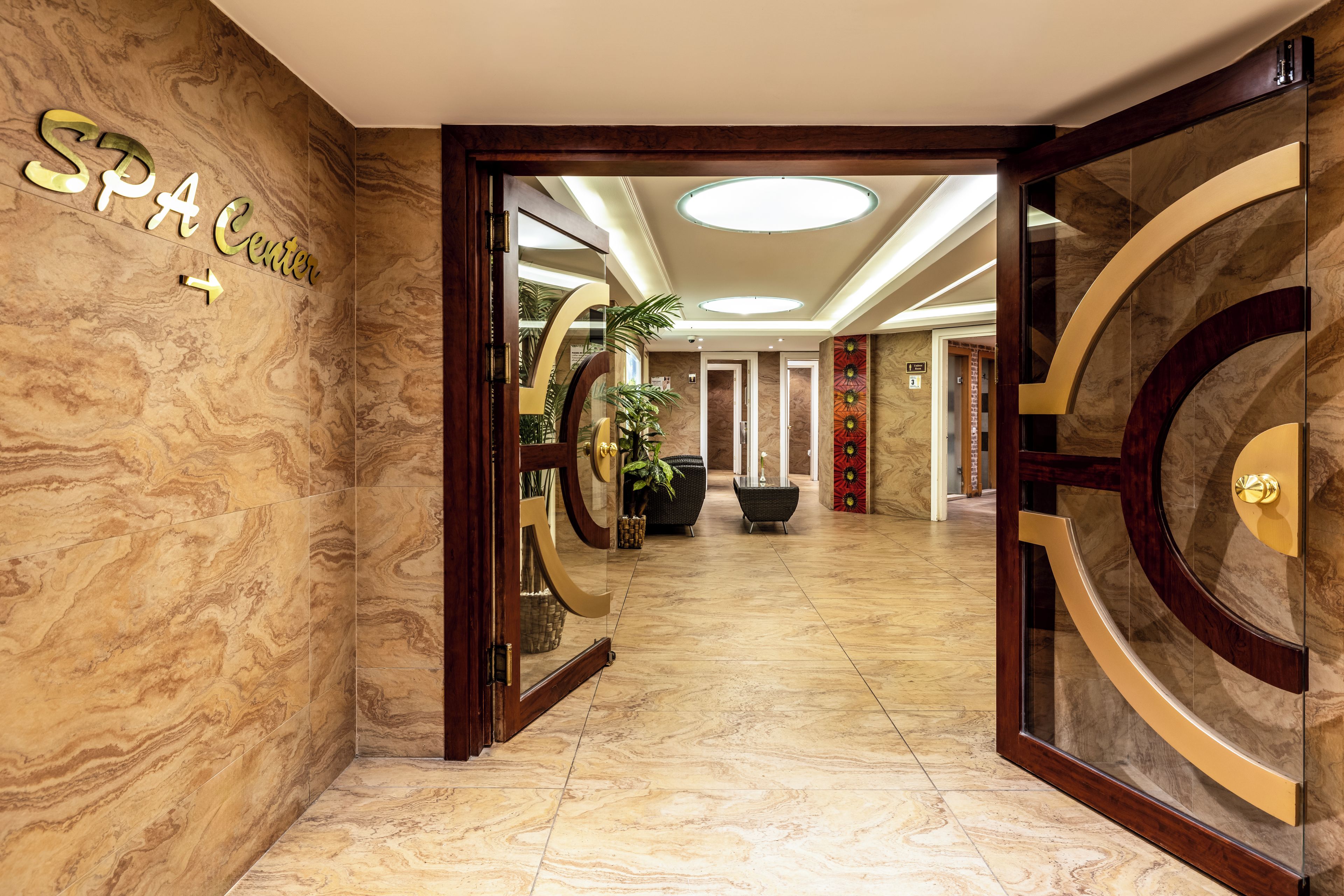Un vestíbulo de hotel con suelo de mármol, una recepción y un cartel que dice 'SPA Center'.