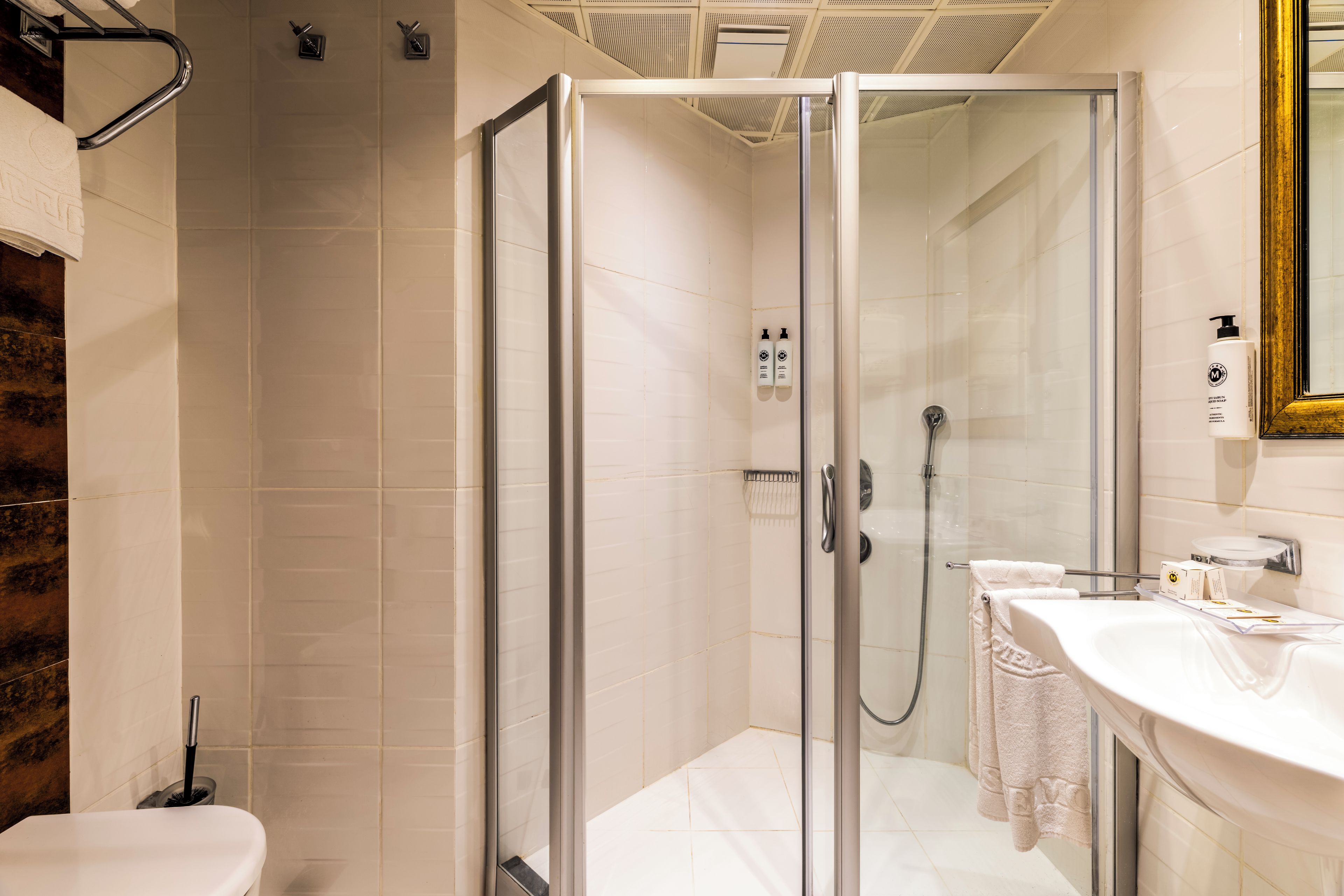 A modern bathroom with a glass-enclosed shower, a white sink, and a mirror.