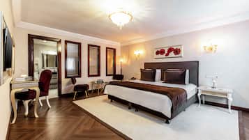 Una habitación de hotel con una cama grande, un escritorio, una silla, un espejo y una araña.