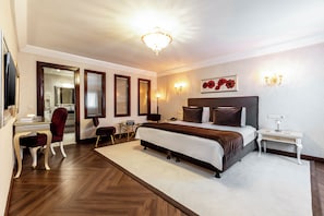 Une chambre d’hôtel avec un grand lit, un bureau, une chaise, un miroir et un lustre.