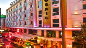 Un hotel con un llamativo letrero 'MOSAIC', varios balcones y un restaurante a nivel de calle.