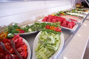 A buffet with various food options including watermelon, cucumbers, and salads.