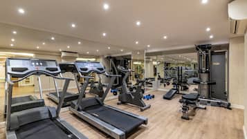 Un gimnasio con cintas de correr, máquinas de pesas y un espejo grande.