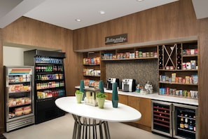 En kiosk med kylskåp för drycker, hyllor fyllda med snacks och drycker samt en kaffemaskin.