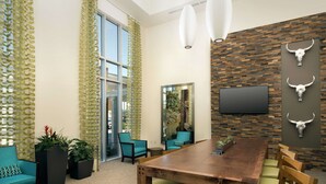 A modern conference room with a wooden table, teal chairs, and a large mirror. - Hilton Garden Inn San Antonio Airport South (San Antonio)
