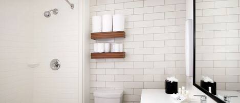 Un baño moderno con ducha de azulejos blancos, bañera, inodoro y tocador con espejo.