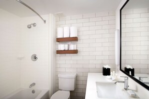 Een bad/douchecombinatie, designer toiletartikelen, handdoeken