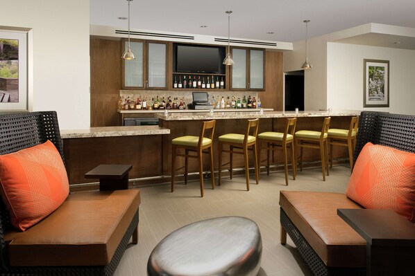 A modern kitchen with a bar area, wooden cabinets, and a flat-screen TV.