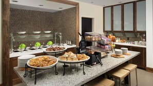 A buffet area with various food items, a bread display, and a coffee station. - Hilton Garden Inn San Antonio Airport South (San Antonio)