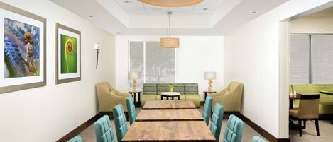 A conference room with a long table and chairs, framed artwork on the walls, and a hanging light fixture.
