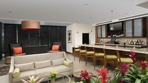 A modern living room with a sofa, chairs, a coffee table, and a bar area with a wine rack. - Hilton Garden Inn San Antonio Airport South (San Antonio)