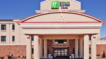 Un Holiday Inn Express & Suites con un llamativo logo H, fachada de ladrillo y una entrada simétrica con columnas.