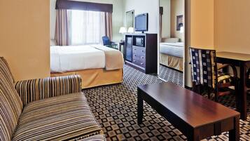 A hotel room with a bed, a sofa, a desk, a television, and a patterned floor.