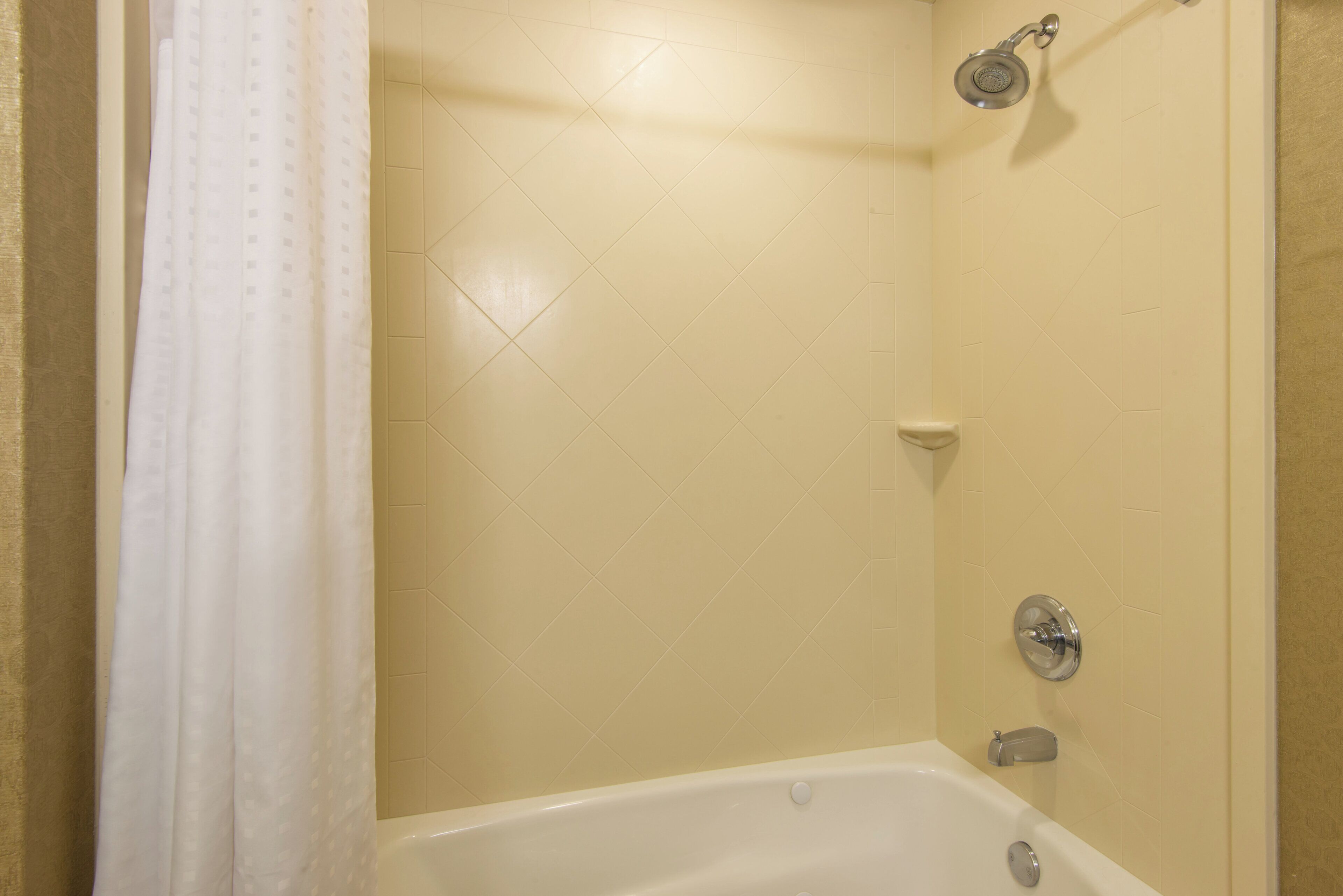 Un baño con bañera, ducha y paredes de azulejos.
