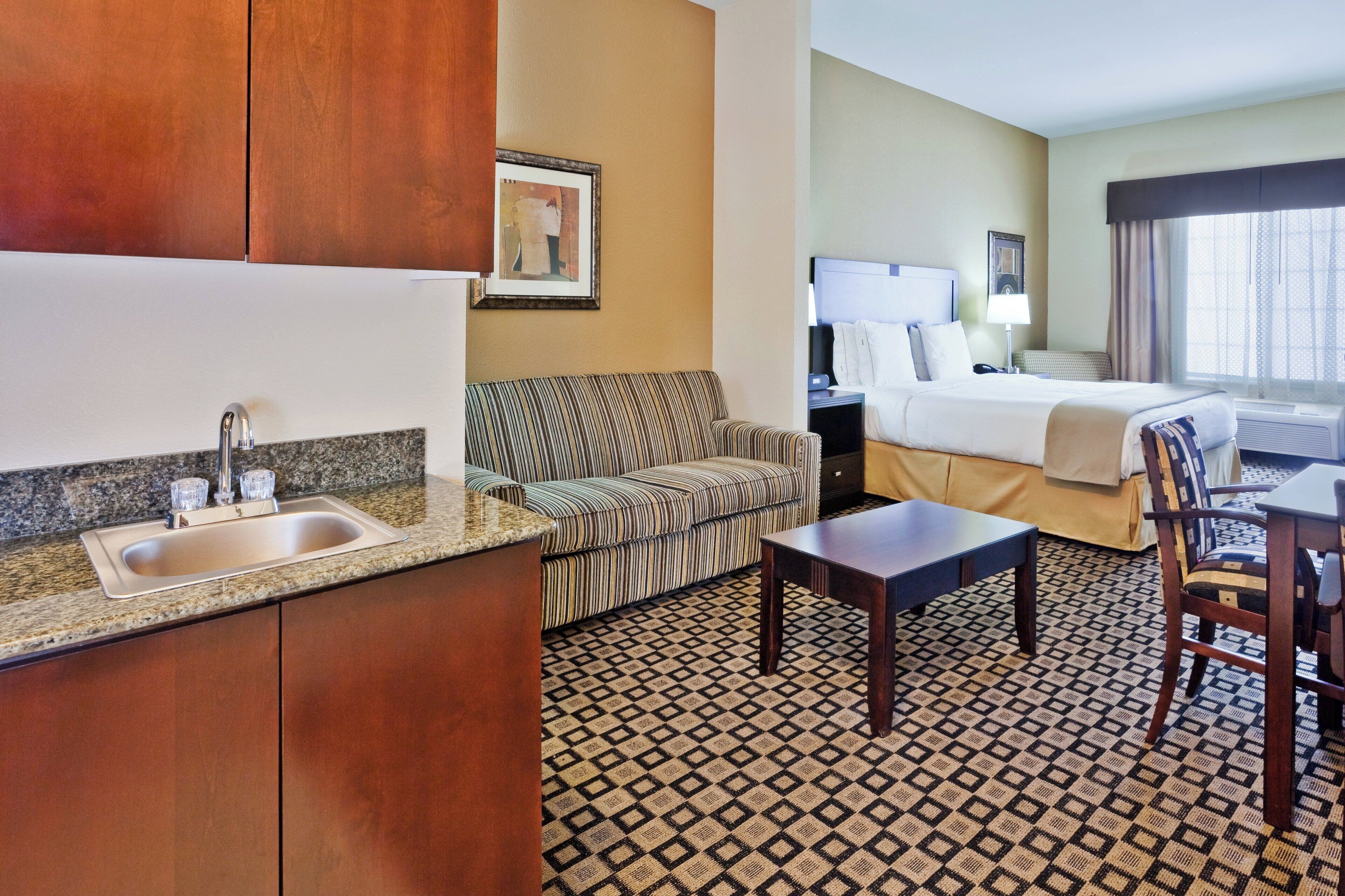 Een hotelkamer met kitchenette, een bank, een bed, een bureau en een stoel.