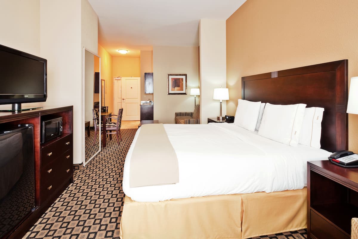 A hotel room with a bed, a TV, a desk, and a chair.