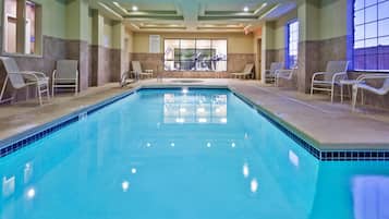 Relax by the pool surrounded by lounge chairs and large windows.