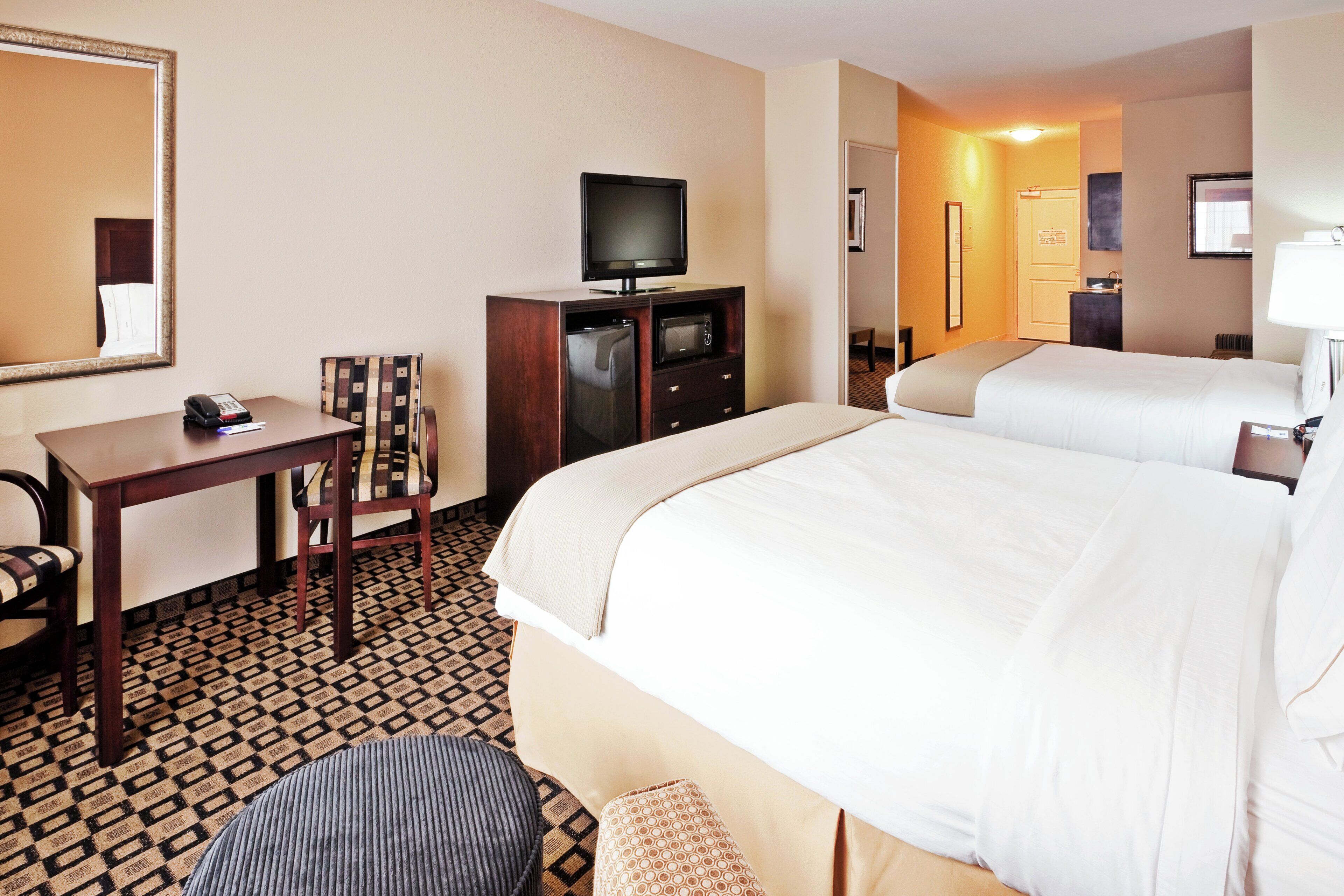 Een hotelkamer met een bed, bureau, televisie, magnetron en spiegel.