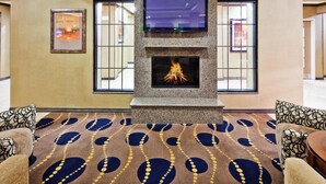 A lobby with a fireplace, patterned carpet, and seating area. - Holiday Inn Express Hotel & Suites Clovis by IHG (Clovis)
