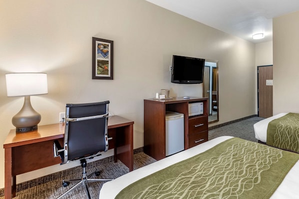 Una habitación de hotel con escritorio, silla, televisión y dos camas.