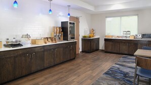 A modern kitchen with wooden cabinets, a large island, and blue pendant lights.