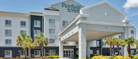 A Fairfield by Marriott Inn & Suites building with a modern design, featuring a covered entrance and a parking lot.