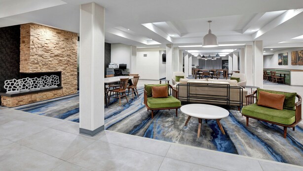 A spacious lobby with a stone wall, modern furniture, and a large rug.