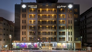 A multi-story hotel with a modern design, featuring a prominent entrance and illuminated signage. - Donatello Hotel (Dubai)
