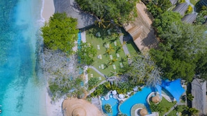Eine Luftaufnahme eines Resorts mit Strand, Schwimmbad und einer Tiki-Bar.