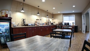 A spacious kitchen with wooden cabinets, a central island, pendant lighting, and a large window providing natural light. - GrandStay Hotel & Suites Perham (Perham)