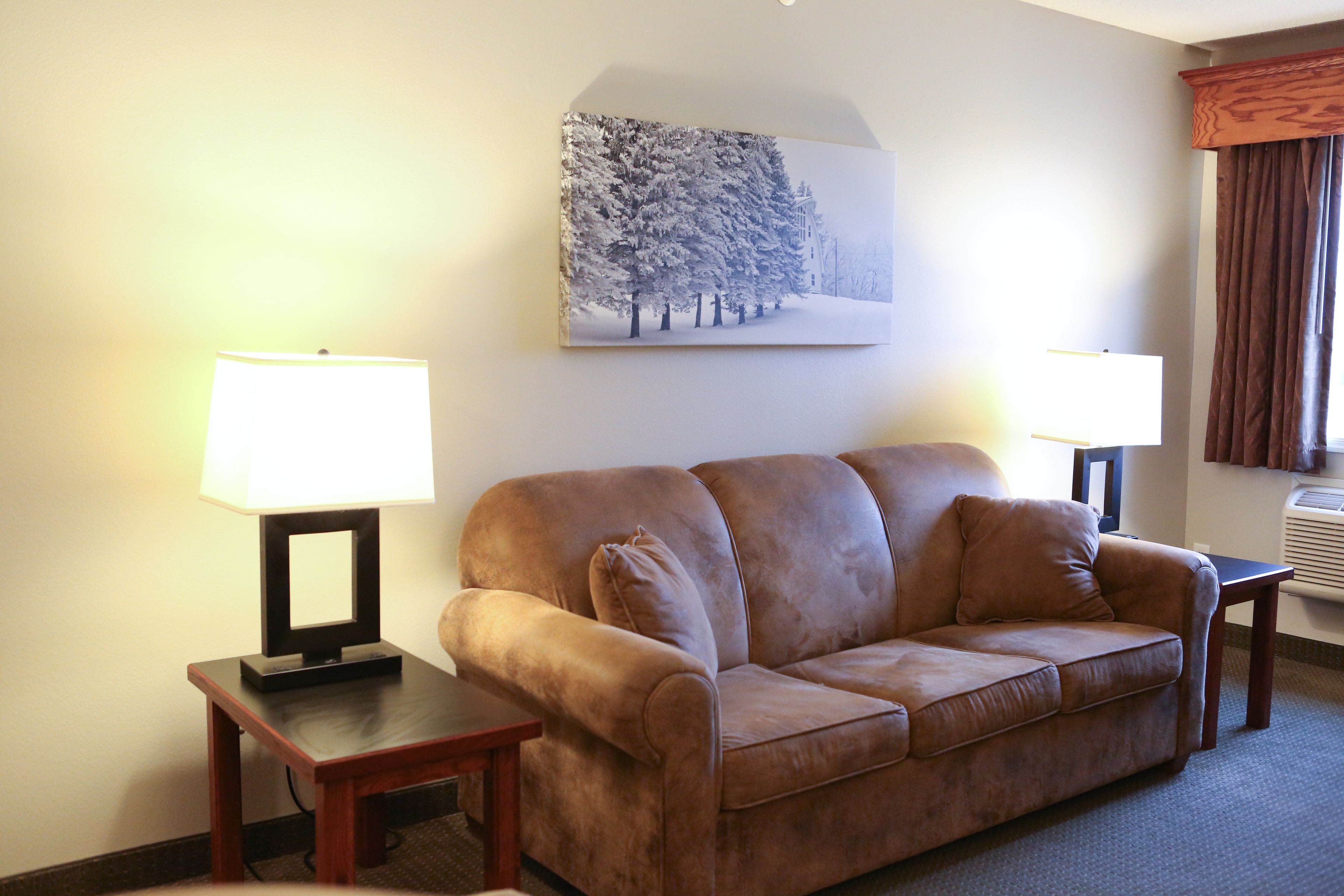 A living room with a brown sofa, two side tables with lamps, and a framed picture on the wall.