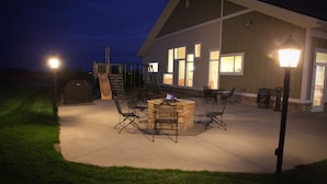 An outdoor patio area with a fire pit, seating, and a swing set. - GrandStay Hotel & Suites Perham (Perham)