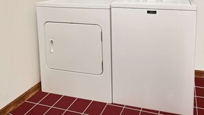 A front view of a white, wall-mounted washer and dryer unit with a control panel on top and a front door with a handle. - Knights Inn Muskogee (Muskogee)