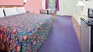 A hotel room with a large bed, a desk with a chair, a television, and a window with curtains. - Knights Inn Muskogee (Muskogee)