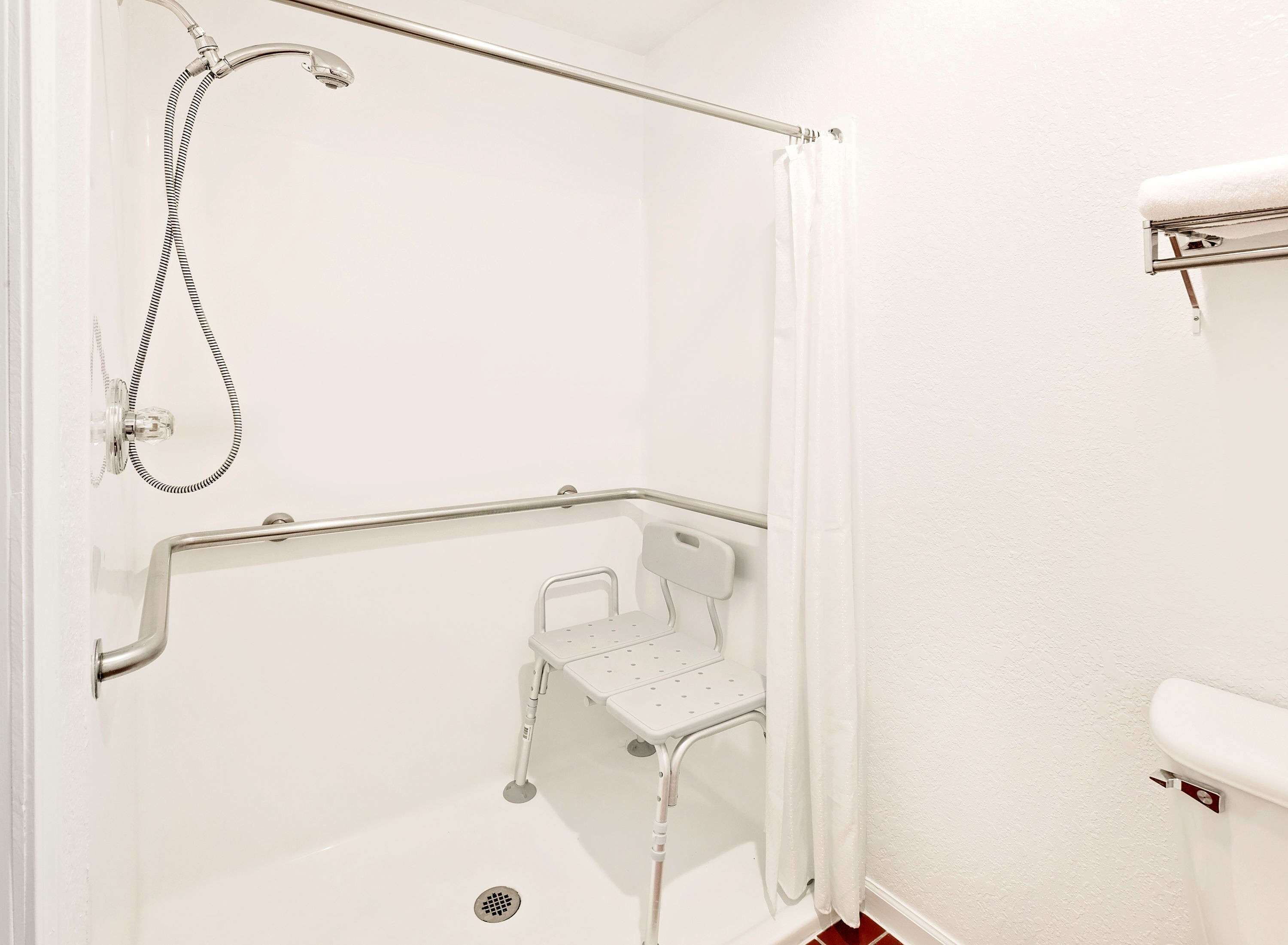 Un espace douche équipé d’une barre d’appui, d’un pommeau de douche et d’un flexible de douche.