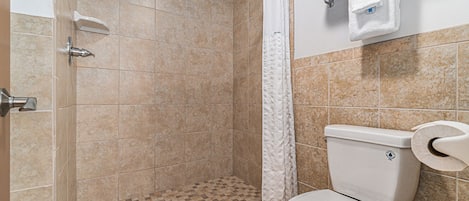 A bathroom with a shower, toilet, and towel rack.
