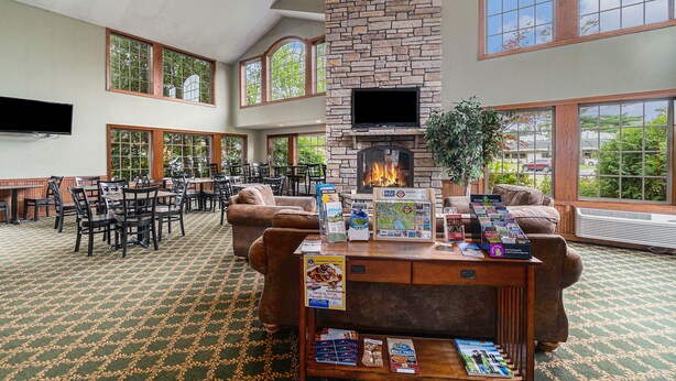 A spacious indoor area with a fireplace, multiple seating arrangements, and large windows offering views of the outdoors.