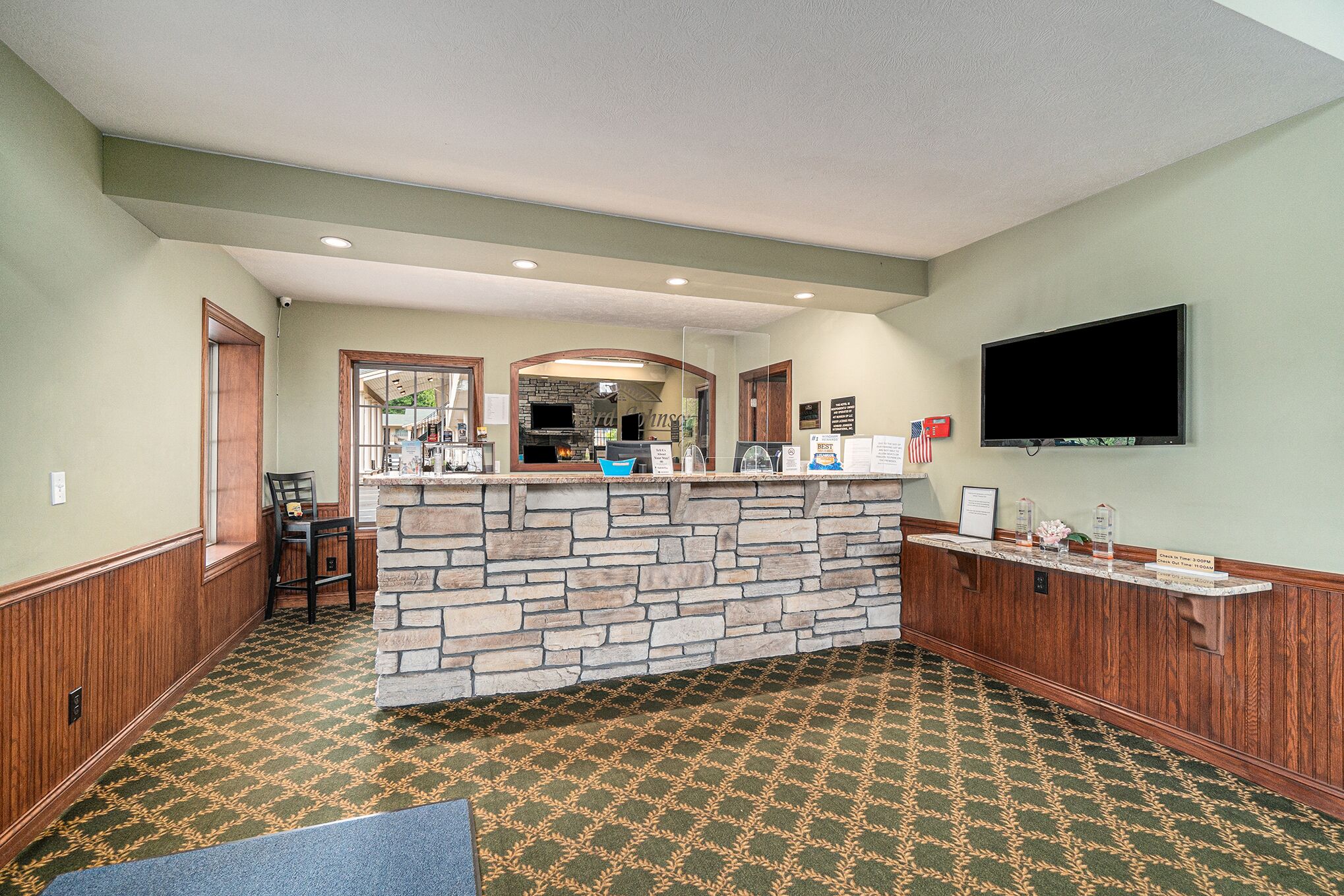 A reception area with a stone counter, a flat-screen TV, and a patterned carpet.