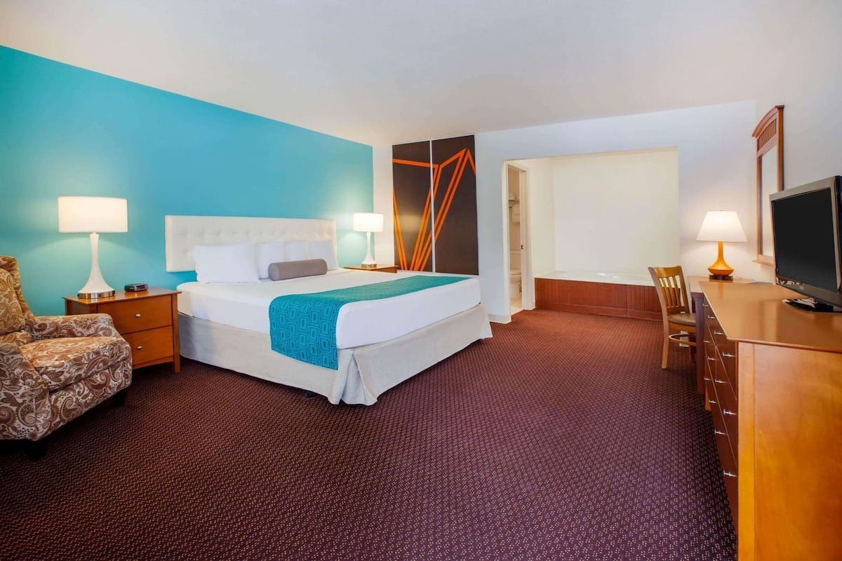 Ein Hotelzimmer mit Bett, Schreibtisch, Fernseher und Stuhl.