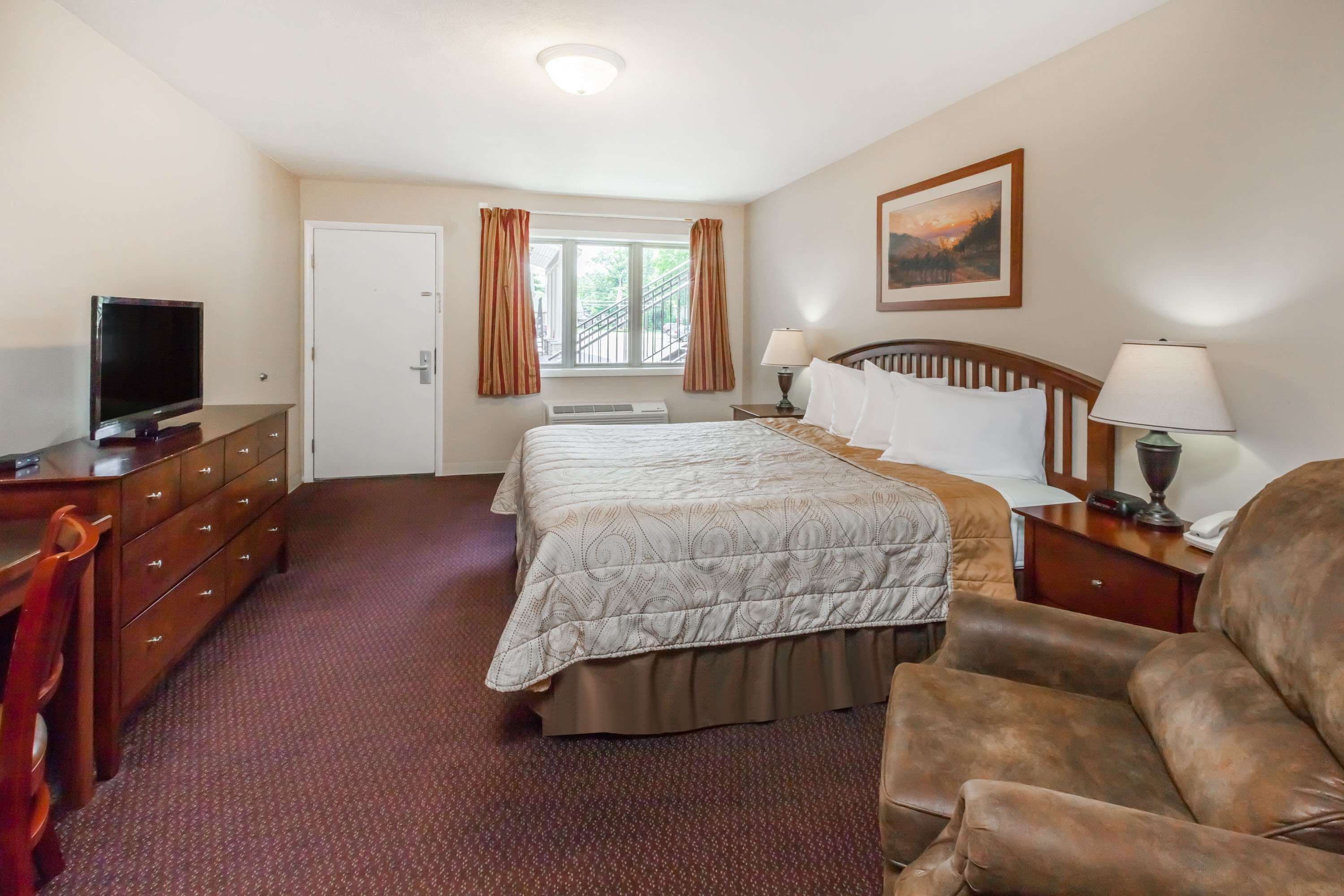 A hotel room with a bed, a TV, a desk, and a chair.
