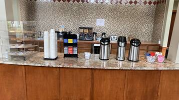 A breakfast bar with a tiled backsplash, a coffee station with three thermos cups, and a menu board.