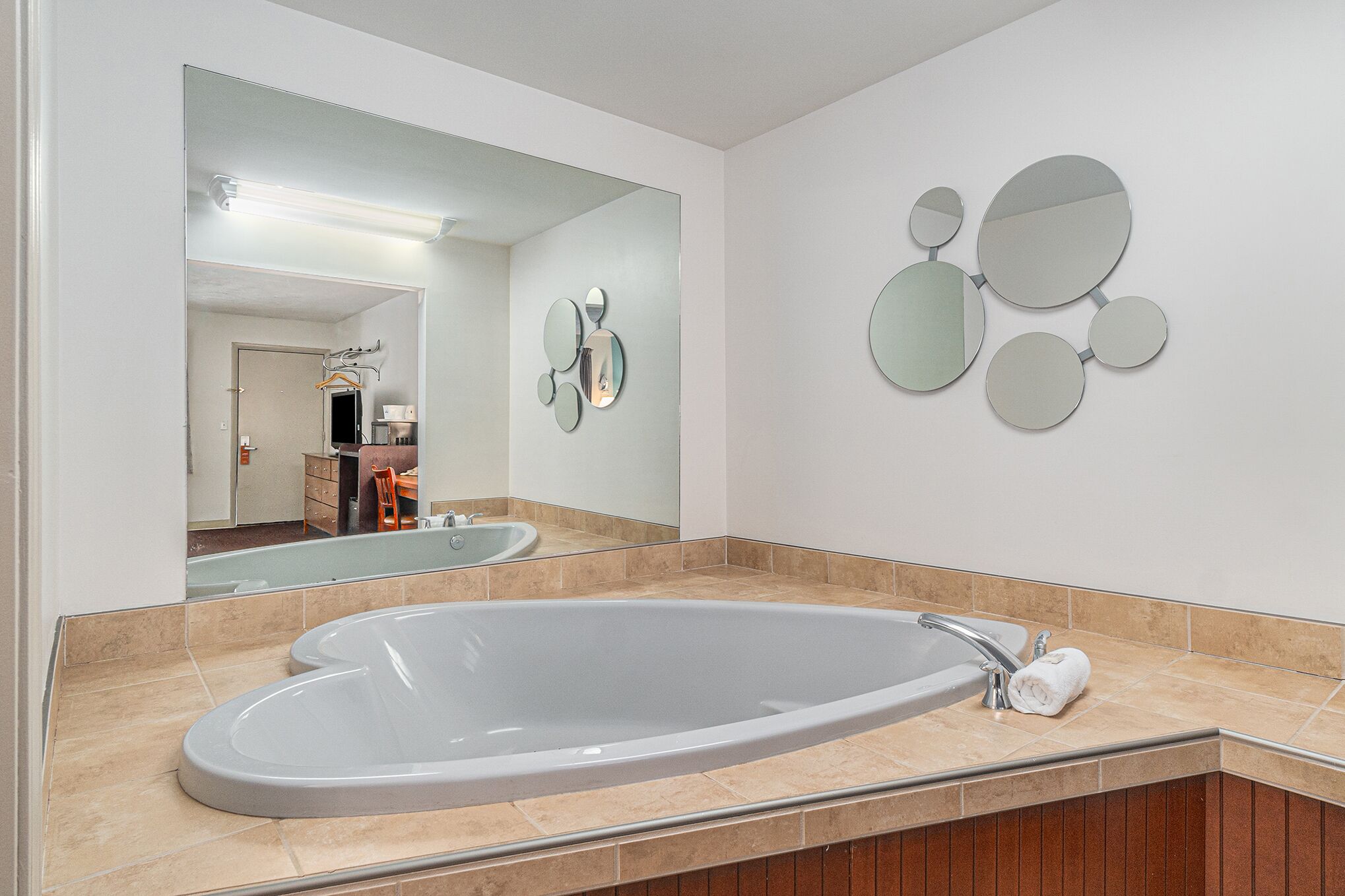 A modern bathroom with a large oval sink, a mirror, and a wall-mounted circular mirror arrangement.