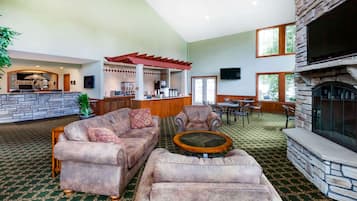 A spacious living area with a stone fireplace, comfortable seating, a kitchen area, and a bar.