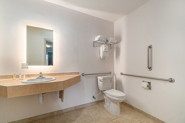 Un baño con lavamanos, inodoro y barras de apoyo.