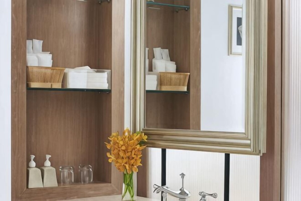 Une salle de bain avec un meuble-lavabo en bois, un miroir et des étagères contenant des articles de toilette.